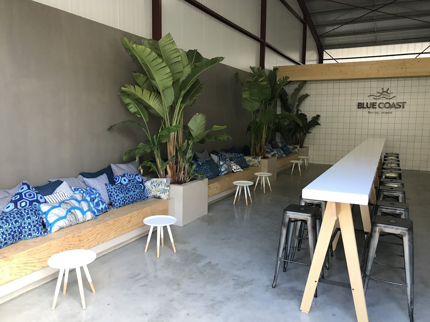 Le taproom vide avec ses plantes, coussins et longue table